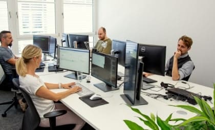 Vier Softwareentwickler sitzen im Büro an Bildschirmen